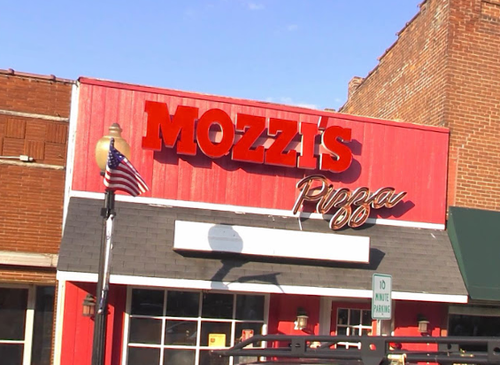Mozzi's Pizza Fortville storefront — bold red sign on a brick downtown building