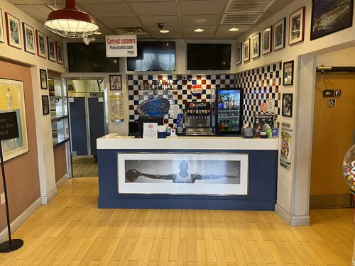 Inside Mozzi's Pizza Greenfield flagship — basketball memorabilia, checkered tile, the original Fieldhouse